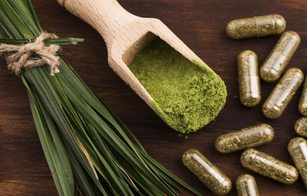 This image showcases a wooden scoop of kratom powder and several capsules, emphasizing the "Benefits of Kratom" and its potential for "Natural Pain Relief." The vibrant green powder is neatly arranged with a bundle of fresh leaves, symbolizing its natural origin