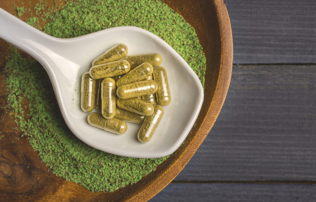 A close-up of kratom capsules and powder highlights the Benefits of Kratom and its potential as a Natural Pain Relief option